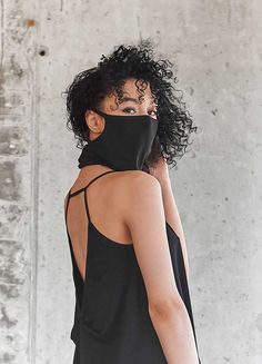 a woman with curly hair wearing a black neck gaiter