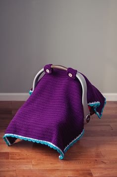 a purple blanket sitting on top of a hard wood floor next to a white wall