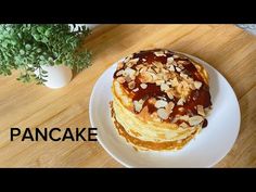 a stack of pancakes sitting on top of a white plate next to a potted plant