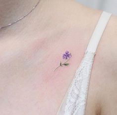 a small purple flower is on the back of a woman's shoulder and chest