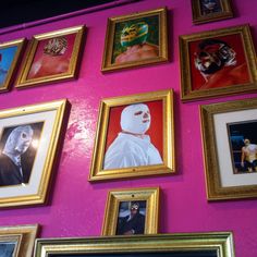 a wall with many framed pictures on it and one has a wrestler painted on it