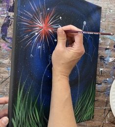 a person is painting fireworks on a canvas