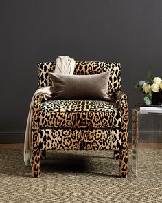 a leopard print chair sitting on top of a rug next to a vase with flowers