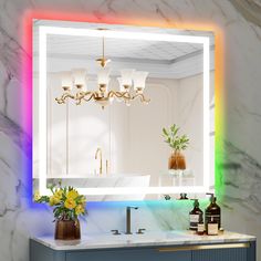 a bathroom with a sink, mirror and lights on the wall above it that are multicolored