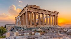 the parthenum temple at sunset, with people walking around in the foreground