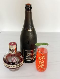 a bottle of champagne next to a glass with a drink in it and another bottle