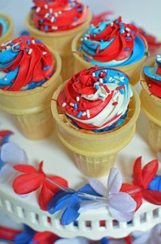 red, white and blue cupcakes in ice cream cones on a cake platter