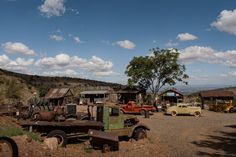 old trucks and cars are parked on the side of a dirt road in an outback town