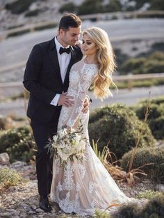 a bride and groom standing together in the desert