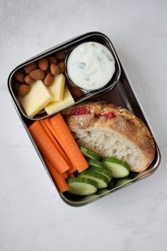 a lunch box with carrots, cucumbers, almonds, bread and yogurt