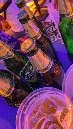 there are many beer bottles on the table and one is in a plastic cup with ice