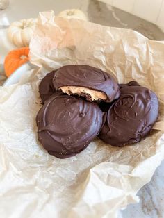 chocolate covered cookies sitting on top of a piece of parchment paper next to pumpkins