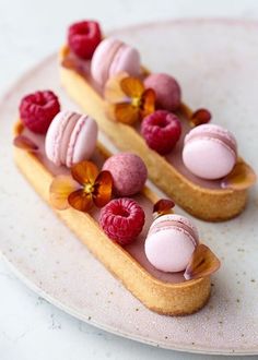 two desserts on a plate with raspberries and other toppings