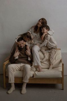 three adults and two children sitting on top of a bed with one child in the middle