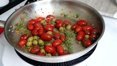 tomatoes and olives are being cooked in a pan on the stove top with water