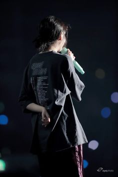 a woman standing in the dark with her back to the camera and holding a toothbrush