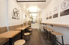 the inside of a restaurant with benches and stools lined up against the wall, along with signs on the walls