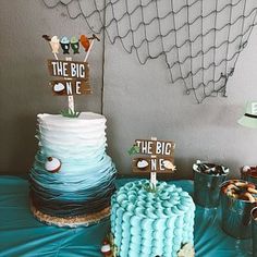 a table topped with two cakes covered in frosting next to cupcakes and candy