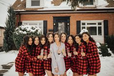 a group of women in red and black flannel holding wine glasses standing in front of a house