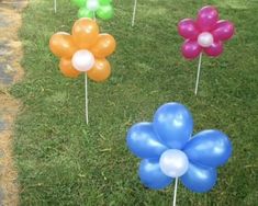 several balloons are placed in the grass with flowers on them and one has a balloon attached to it