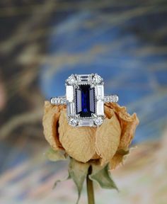 a diamond and sapphire ring on top of a rose