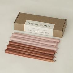 four pink and brown candles sitting in front of a box