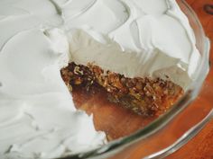 a pie with white frosting and walnuts on top sitting on a wooden table