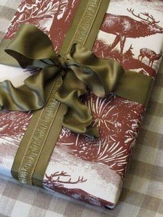 a present wrapped in brown and white paper with a green bow on the top, sitting on a checkered table cloth