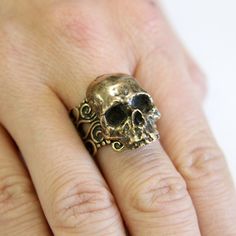 a person's hand with a skull ring on it