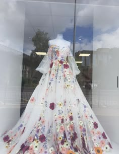 a white dress with flowers on it in a window