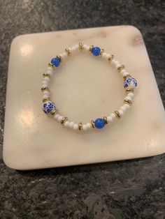 a blue and white beaded bracelet on a marble plate with gold accents, sitting on top of a marble slab