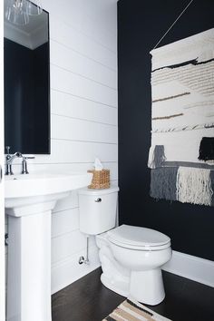 a white toilet sitting next to a bathroom sink under a large framed painting on the wall