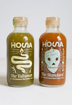 two bottles of hot sauce sitting next to each other on a white surface with the words hona and the tailman