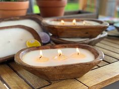 three candles in wooden bowls sitting on a table