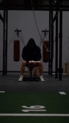 a man squatting on a bench in a crossfit gym with no shoes