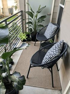 two black chairs sitting on top of a balcony next to plants and potted plants