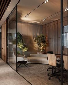 an office with glass walls and plants on the wall, along with two chairs that are facing each other