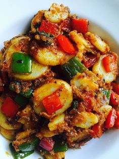 a white plate topped with pasta covered in sauce and veggies on top of it