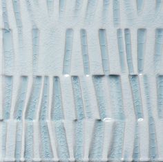 an abstract pattern made up of white and light blue paint on a wall with vertical lines