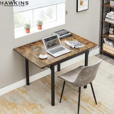 a laptop computer sitting on top of a wooden desk next to a chair and window