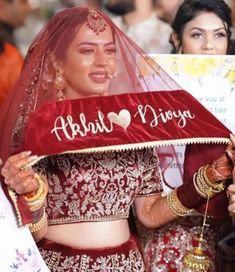 a woman in a red and white wedding outfit holding up a sign