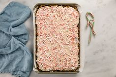 a baking dish with sprinkles and candy canes next to it on a marble surface