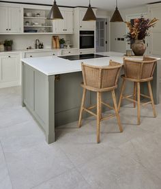 two wicker bar stools sit at an island in the middle of a kitchen