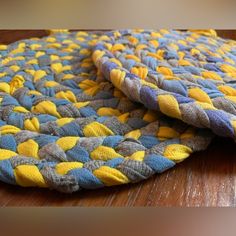 two pieces of cloth sitting on top of a wooden table with yellow and blue colors