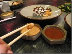 chopsticks with dipping sauce in small bowls on a counter top next to other food items