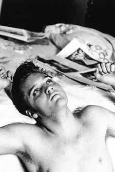 a shirtless man laying on top of a bed next to another person with his eyes closed