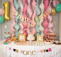 a table with balloons, streamers and cake at a first birthday party for a one year old