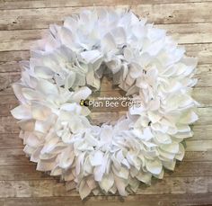 a white wreath with large ruffles is on a wooden table and has the words don't be afraid written in it