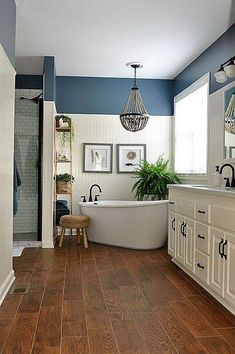 a bathroom with blue walls and wood flooring is pictured in this image, the bathtub has been painted white