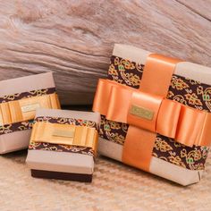 three small boxes with bows on them sitting next to each other in front of a wooden background